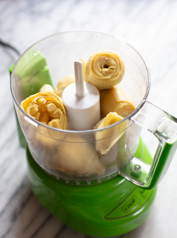 small green food processor with artichoke hearts in it