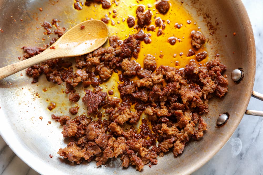 saute pan with cooked crumbled chorizo with wooden spoon