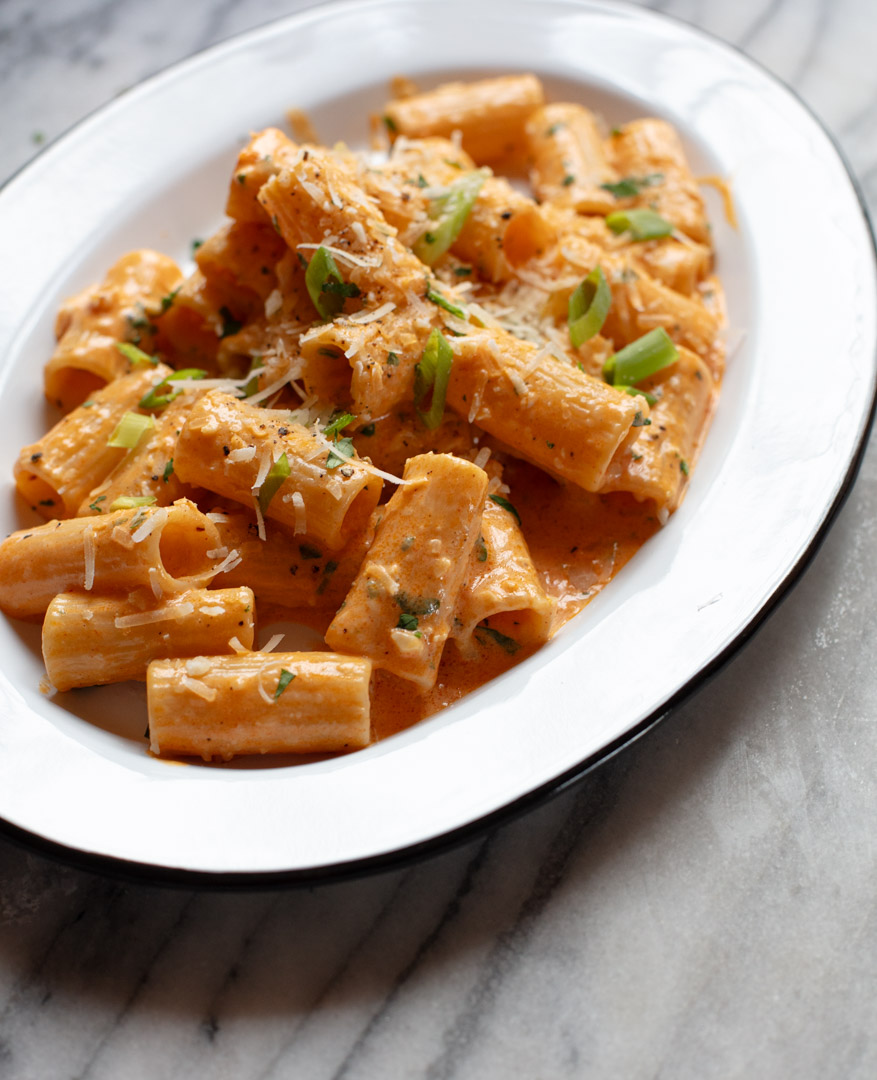 Creamy gochujang pasta with rigatoni, scallions, and parmesan served on a white platter
