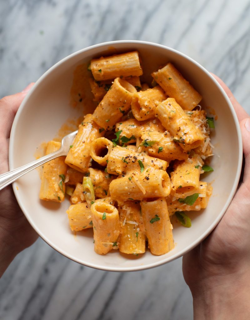 hands holding creamy gochujang pasta bowl