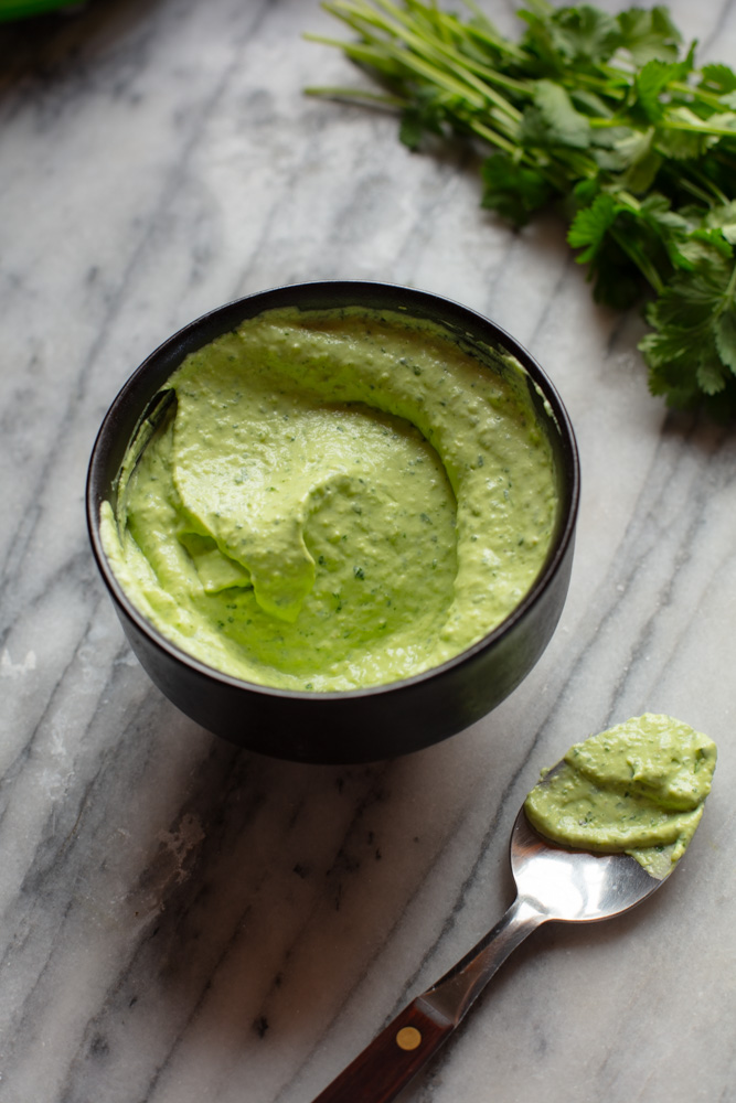 avocado crema in a bowl and on a spoon with fresh cilantro in a corner