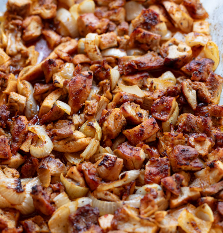 charred chicken pieces in baking dish