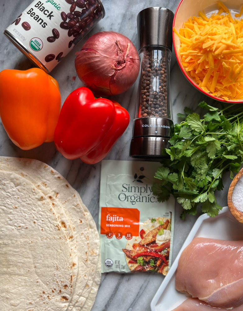 ingredients for chicken fajita wrap. Flour tortillas, fajita seasoning, bell peppers, can of black beans, shredded cheese, cilantro, chicken breast
