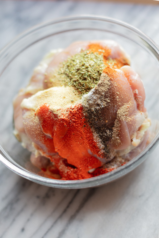 raw chicken thighs with paprika, oregano, garlic powder on top