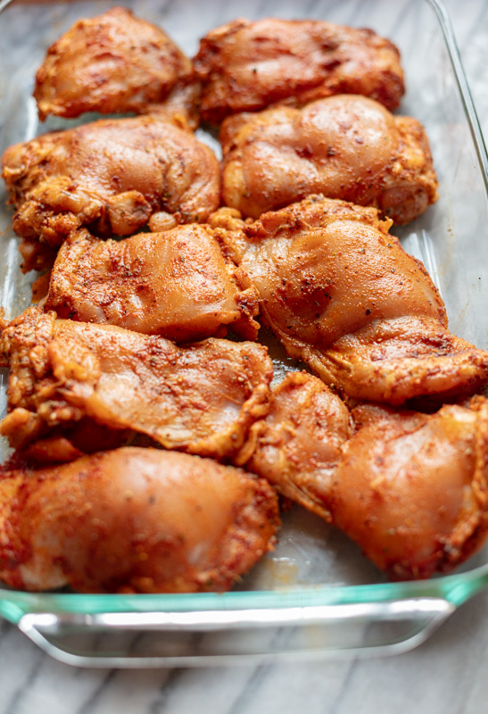 seasoned raw chicken thighs in glass baking dish