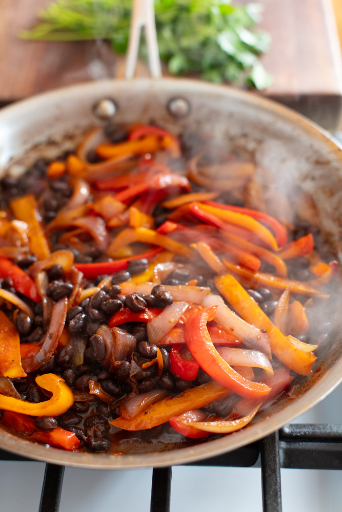 stainless pan with saut&eacute;ed bell peppers, onions, and black beans 
