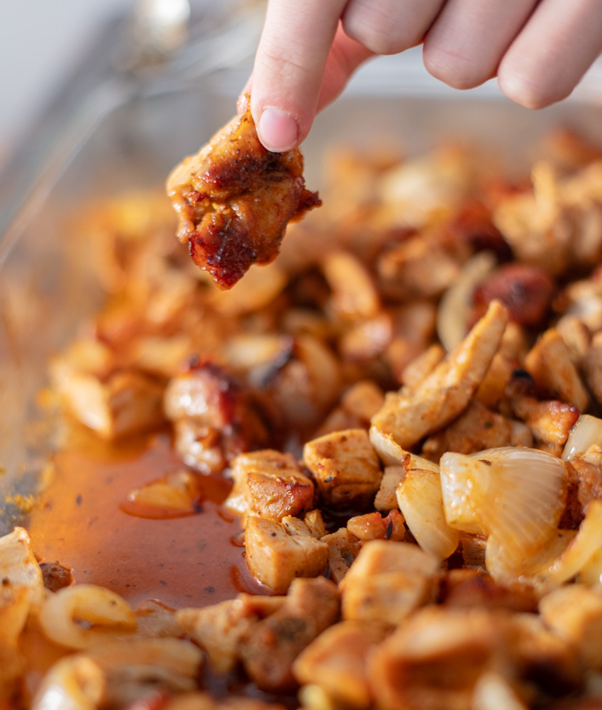fingers holding charred chicken piece