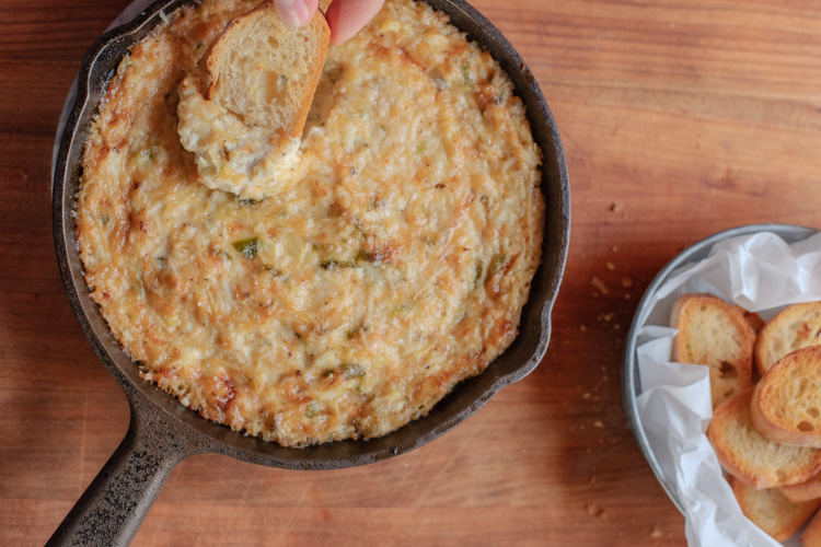 cast iron skillet with jalapeno artichoke dip with crostini
