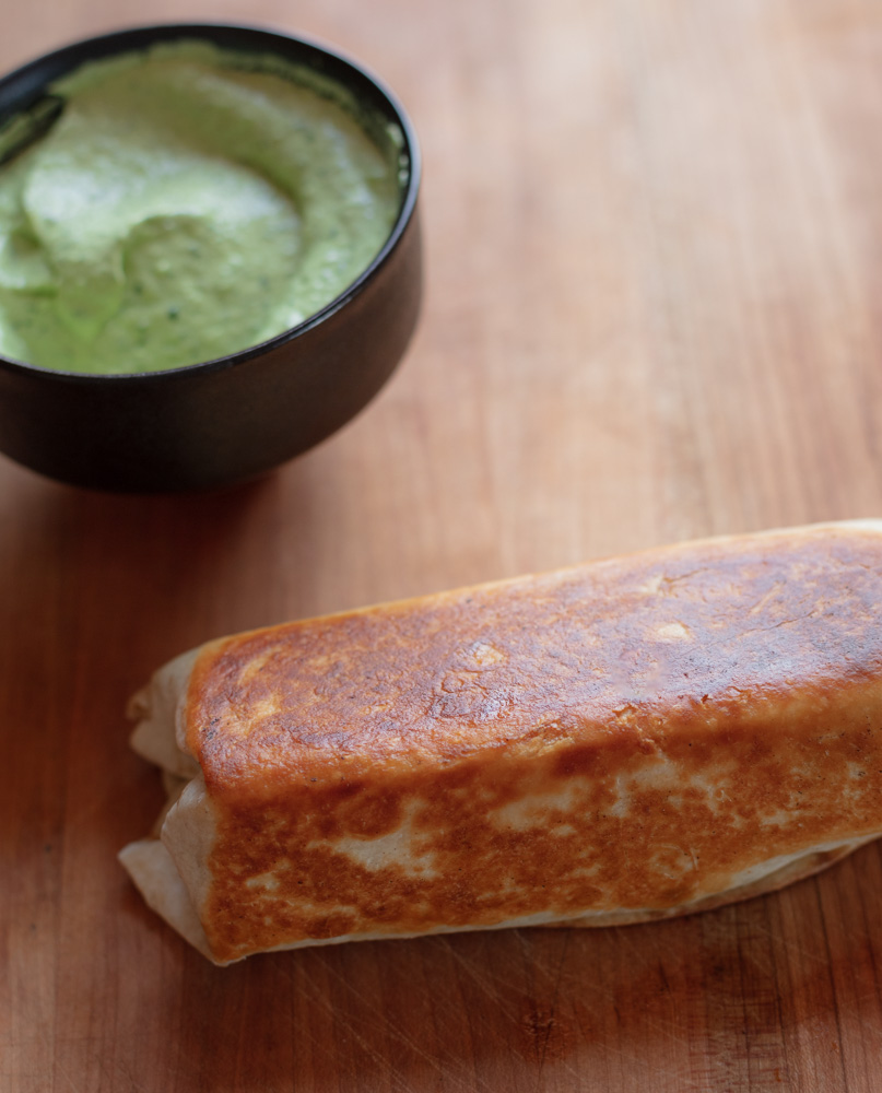 toasted chicken fajita wrap with bowl of avocado crema