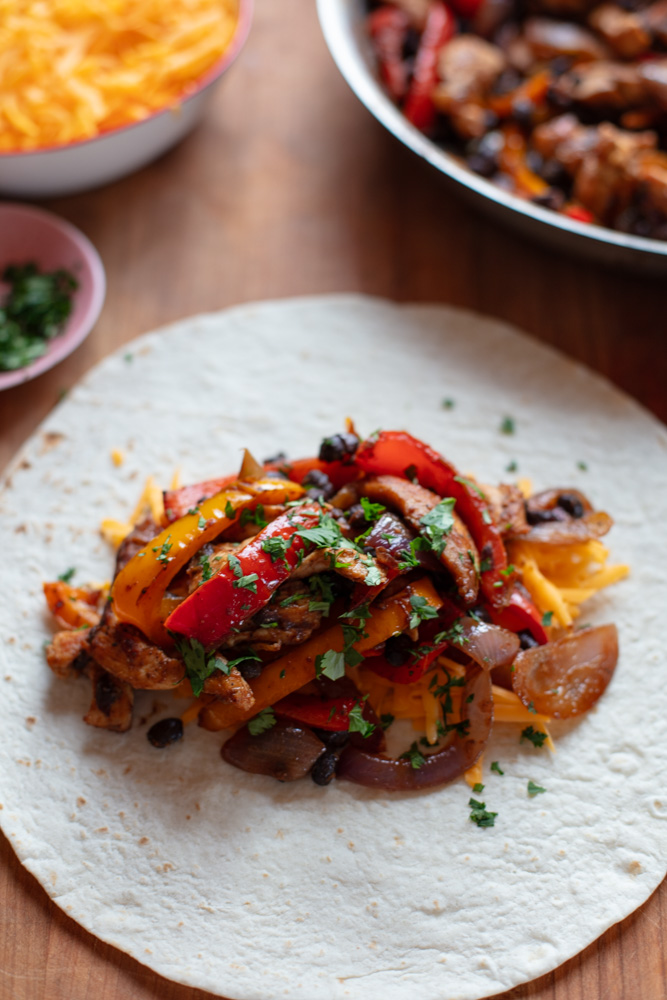 flour tortilla topped with chicken fajita ingredients and parsley