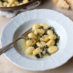 gnocchi with sage butter sauce in shallow bowl with grated parmesan