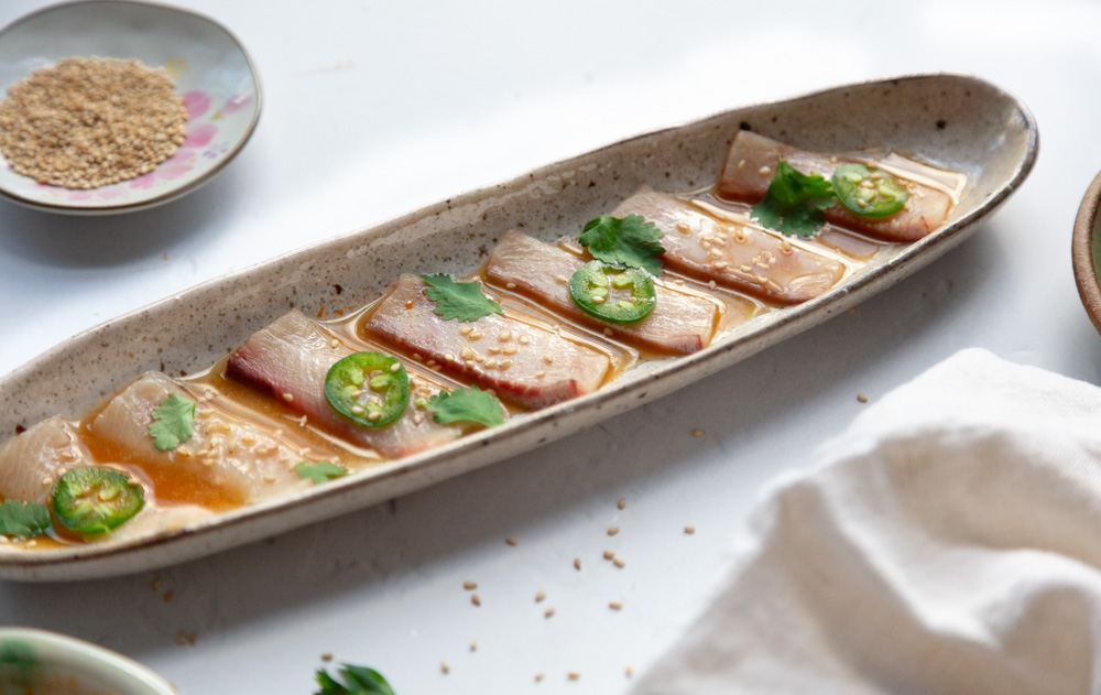hamachi crudo in narrow plate with garnish