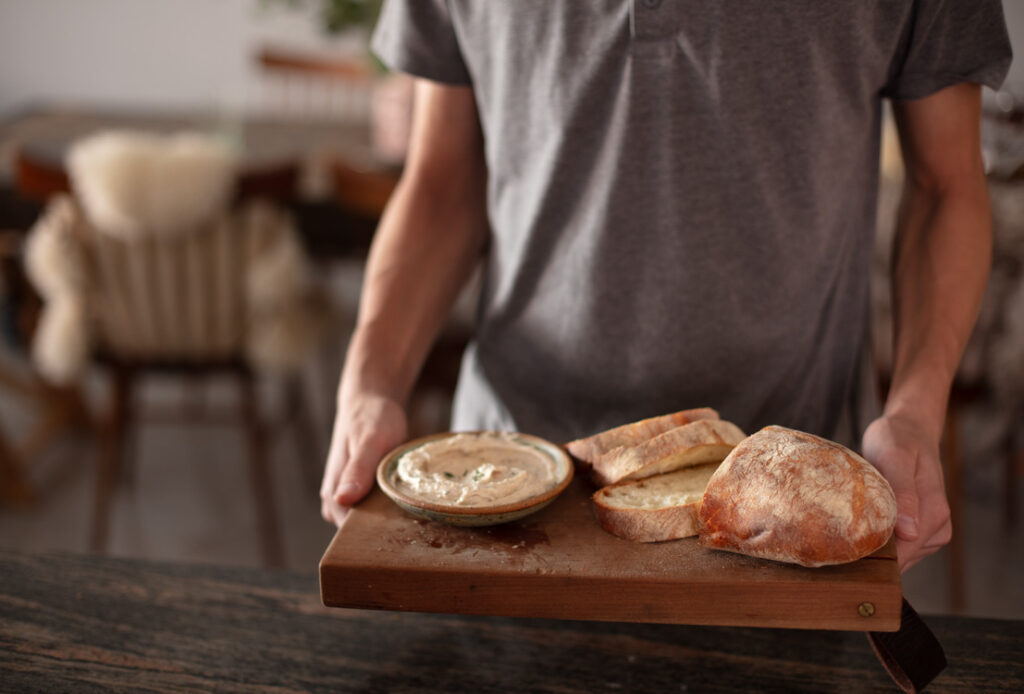 person holding a cutting board with bone marrow butter and bread