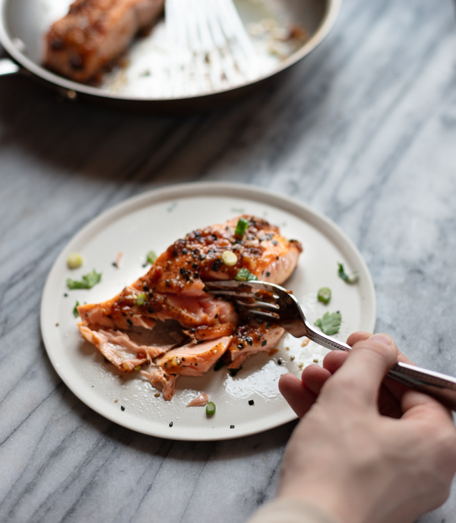 hand holding fork cutting into salmon