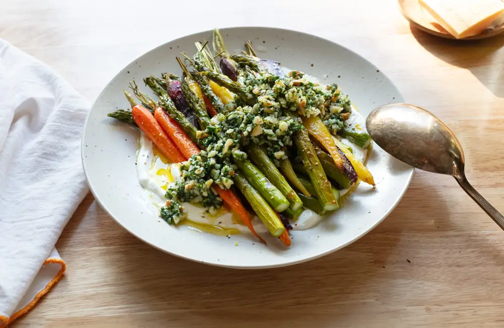 Roasted asparagus and carrots on a bed of yogurt topped with pesto.