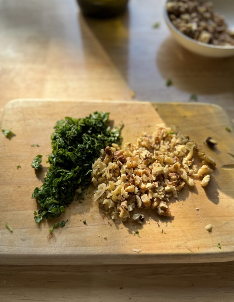 Walnuts and basil chopped on a small cutting board.