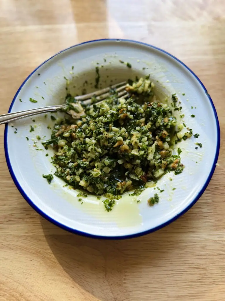 Chunky pesto mixed together in a small bowl.