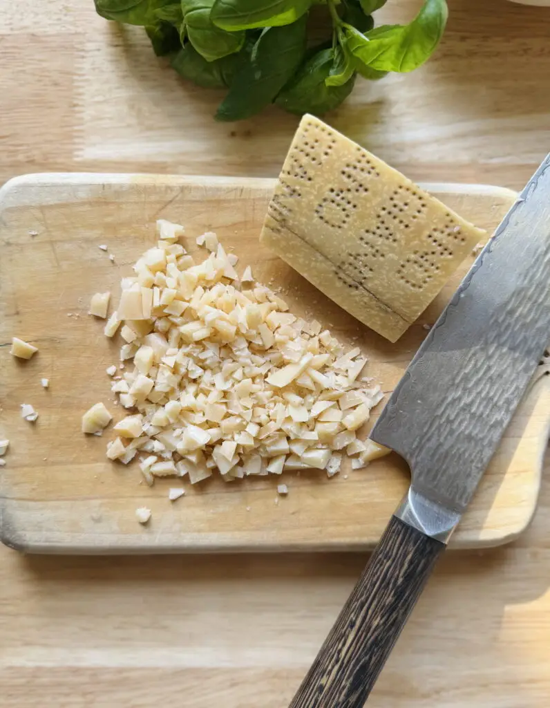 Parmesan cheese chopped into small pieces on a cutting board.