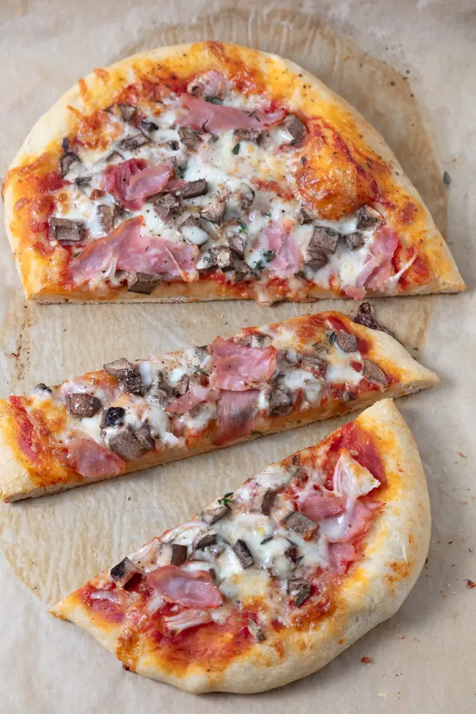 oval pizza cut into slices on parchment paper