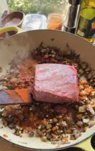 ground beef over cooked veggies in pot