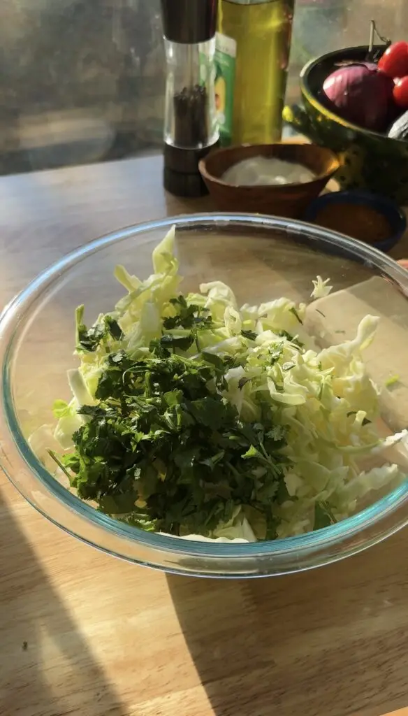 chopped cabbage with cilantro in glass bowl