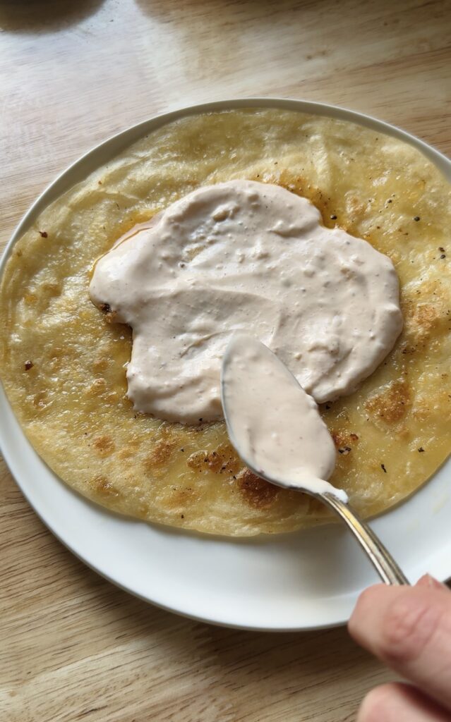 cooked tortilla on a white plate with sauce spooned on top