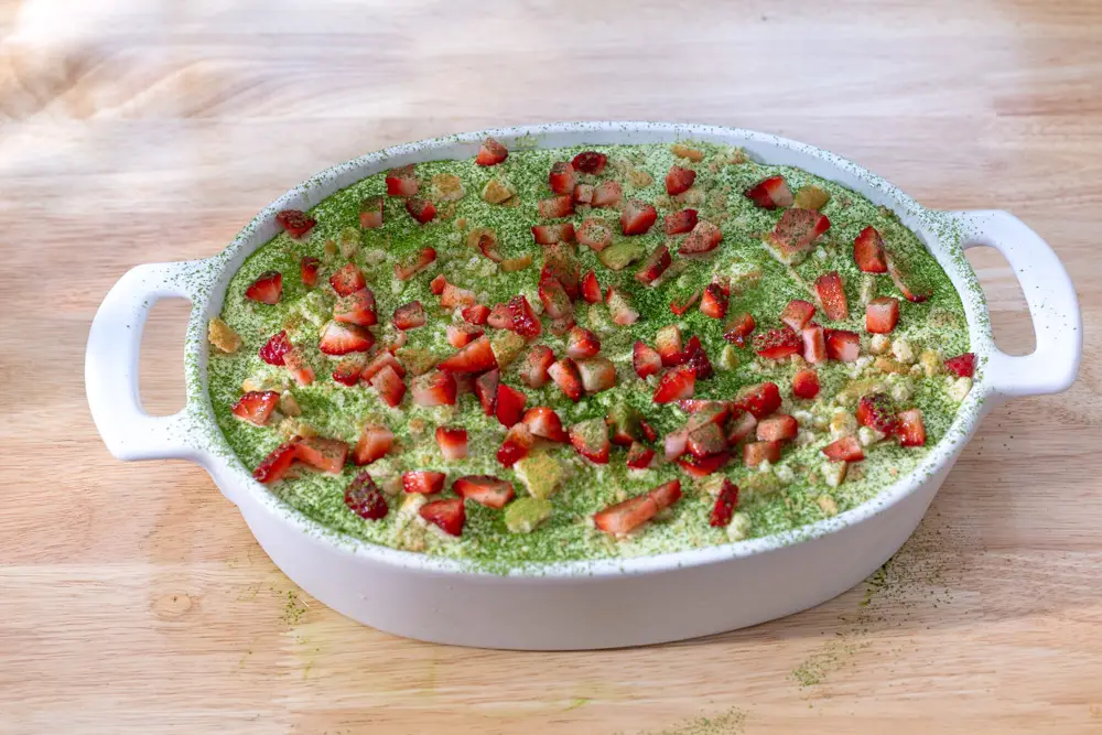 Strawberry banana pudding with matcha served in a serving platter with diced strawberries on top.