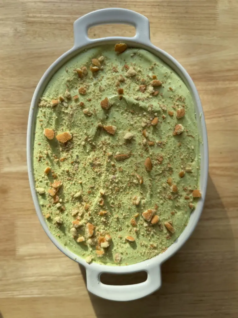 Overhead shot of strawberry banana pudding with matcha in a serving dish with crumbled Nilla wafers on top.