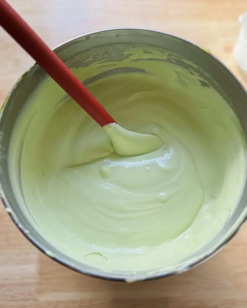 Whipped cream mixed with matcha powder in a mixing bowl.