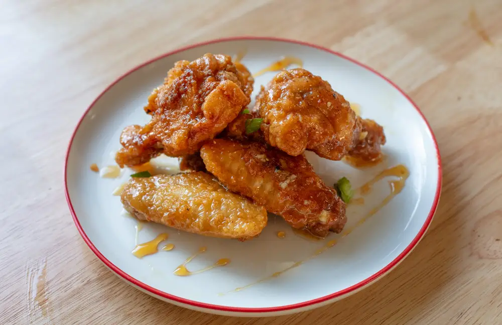 Garlic hot honey chicken wings on a plate with a drizzle of hot honey on top.