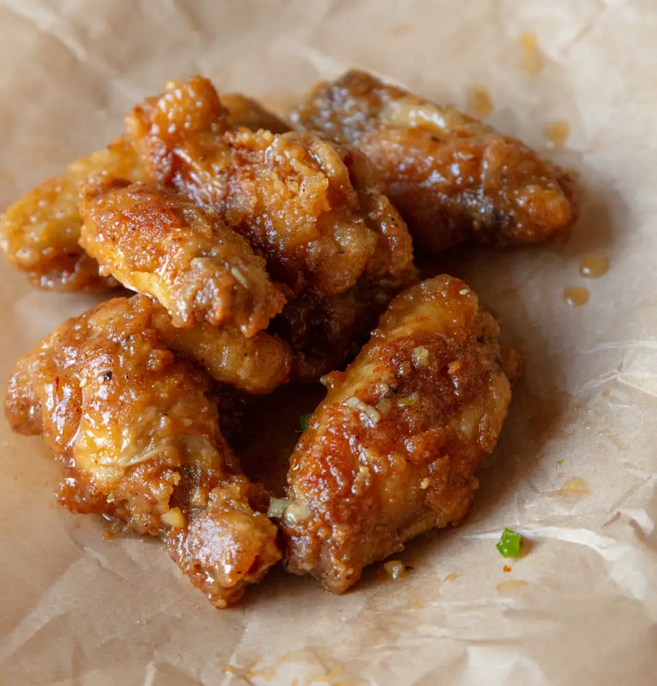 Crispy hot honey chicken sings on a piece of parchment paper.