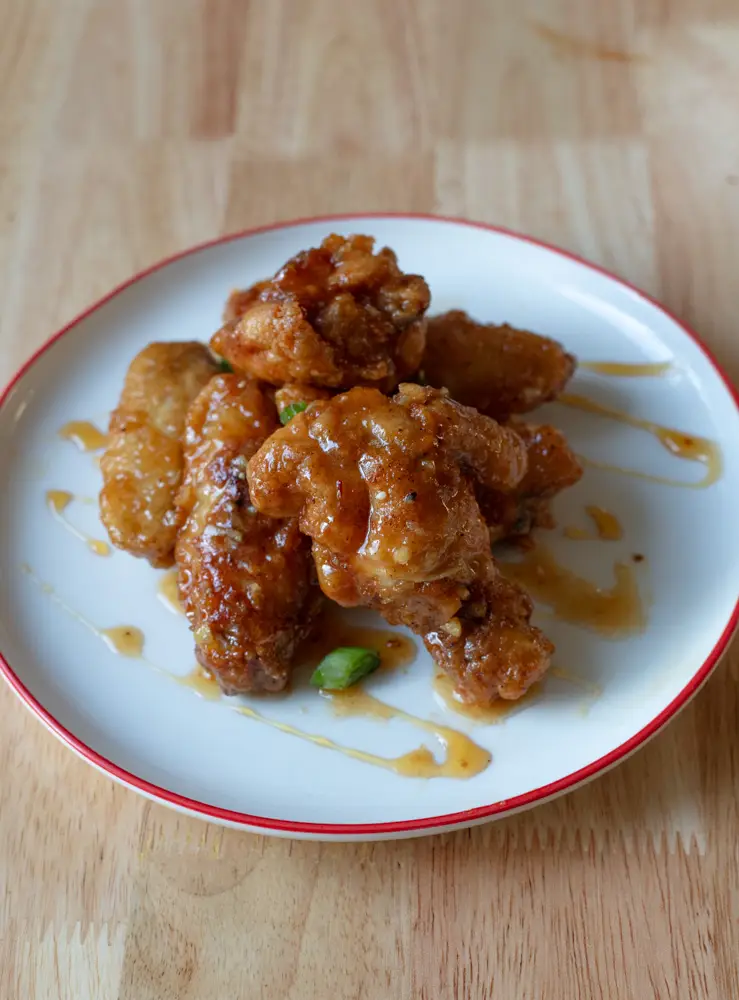Pile of hot honey wings on a plate drizzled with hot honey on top.