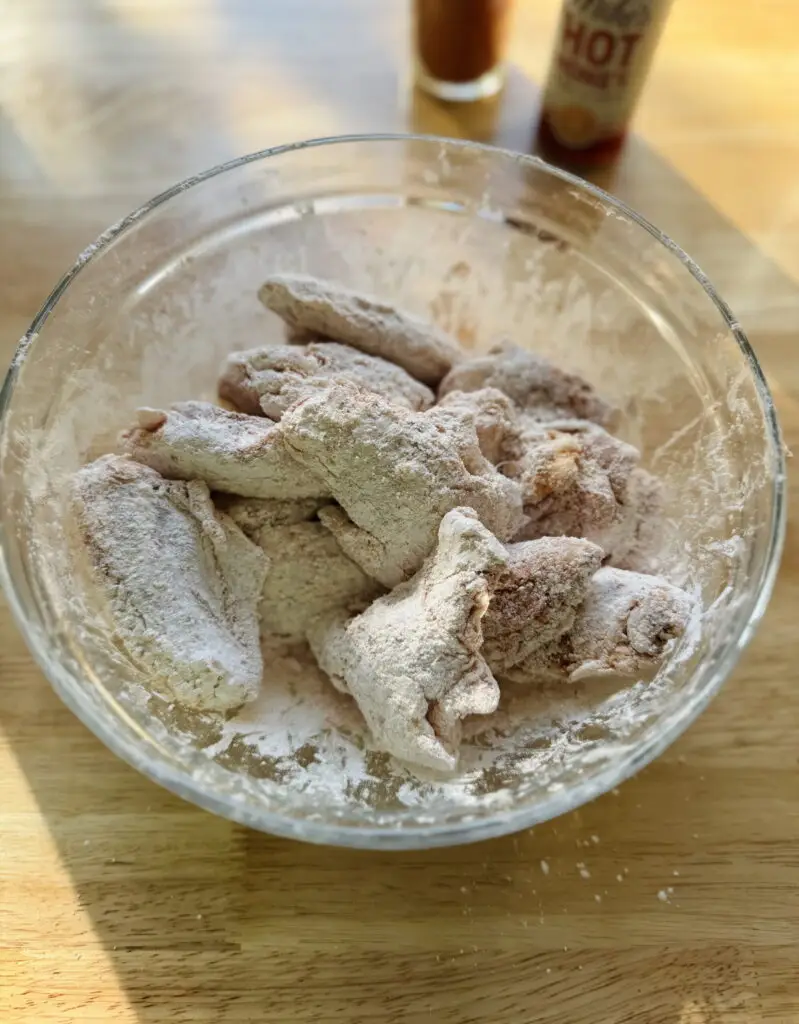 Chicken wings mixed well with the cornstarch and seasonings in a mixing bowl.