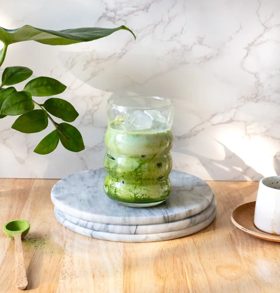 Side view of matcha with milk and ice in a glass.