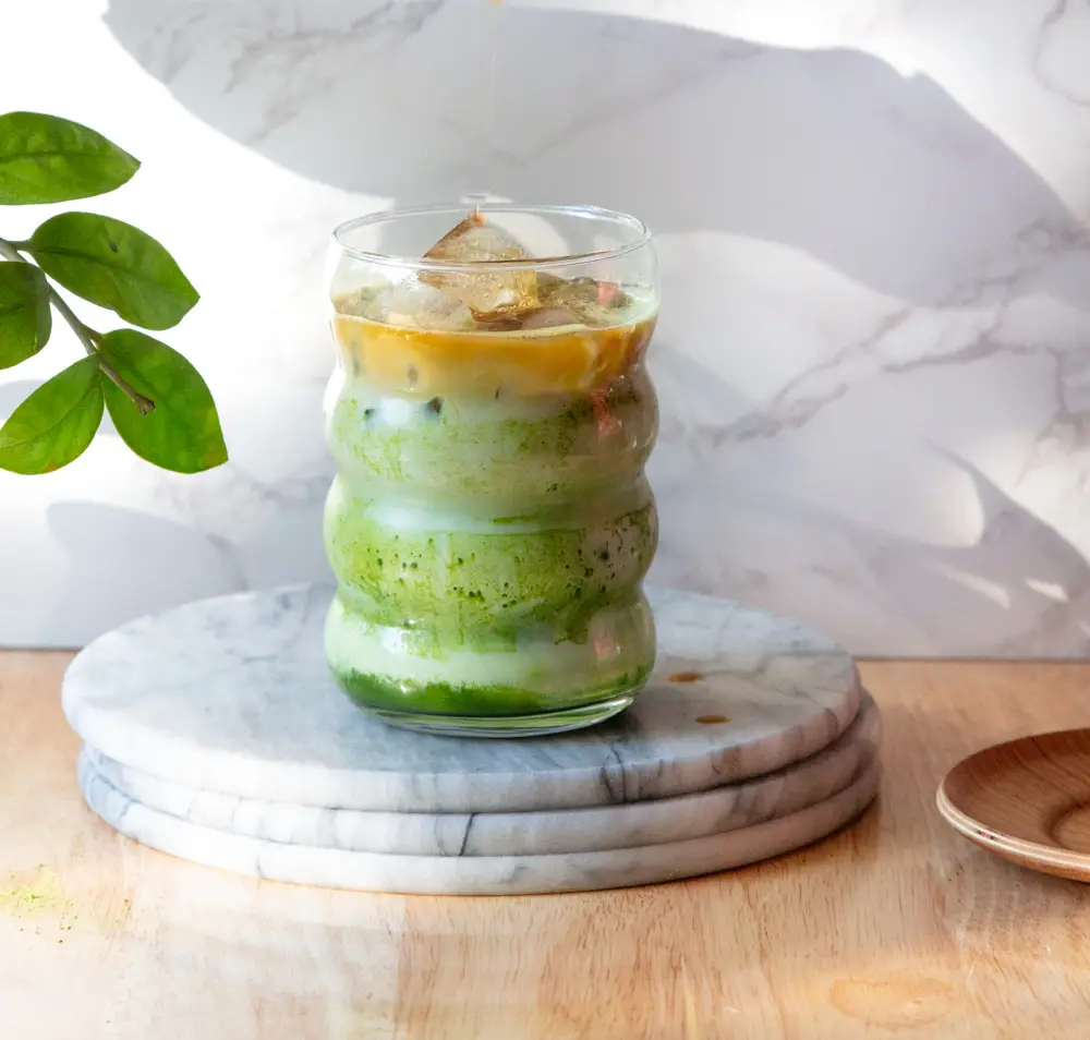 Side view of an iced dirty matcha latte with layers of matcha and coffee.