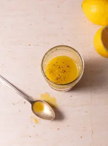 Lemon maple dijon vinaigrette in a jar next to a spoon.