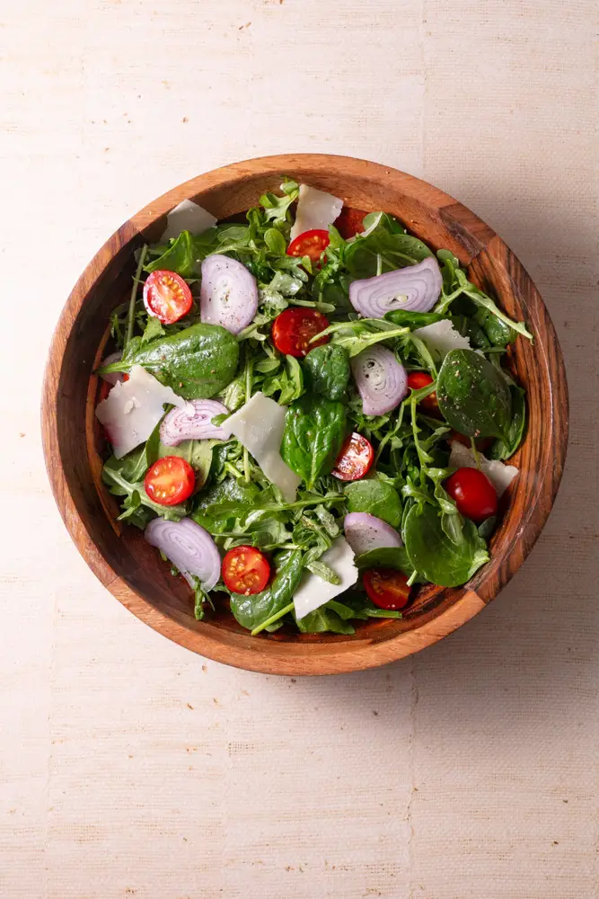 Overhead shot of spinach arugula salad with maple dijon dressing.