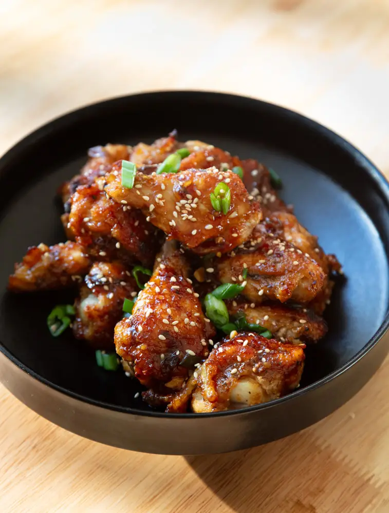 Soy garlic chicken wings piled onto a black plate.