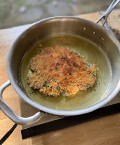 Frying the chicken schnitzel in a pan with oil.