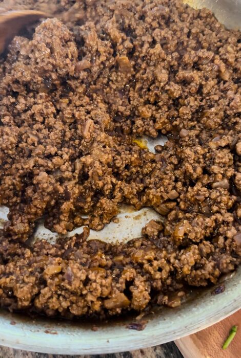 Close-up of seasoned ground beef saut&eacute;ing in a skillet with onions, perfectly browned and ready for assembling the Cheesy Beef & Bean Burrito.