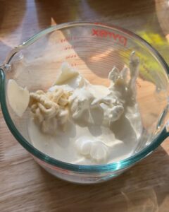 blue cheese dressing base with mayo, sour cream, and cream in a Pyrex cup on wood surface