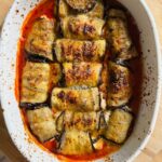 freshly baked eggplant rollatini in tomato sauce with golden cheese topping, beautifully caramelized and ready to serve in a white baking dish