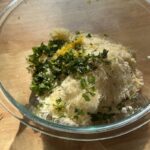 a glass bowl filled with creamy ricotta, parmesan, garlic, fresh herbs, and lemon zest ready to be mixed into a flavorful filling