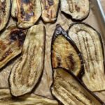 golden brown, tender roasted eggplant slices cooling on a parchment-lined baking sheet