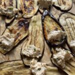roasted eggplant slices topped with scoops of herbed ricotta mixture, ready to be rolled