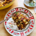 sauteed cabbage with crispy bacon and caramelized onions served with sour cream on a patterned plate
