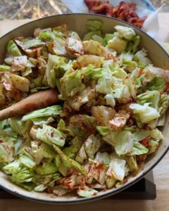 chopped green cabbage added to skillet with spices for sauteed cabbage recipe