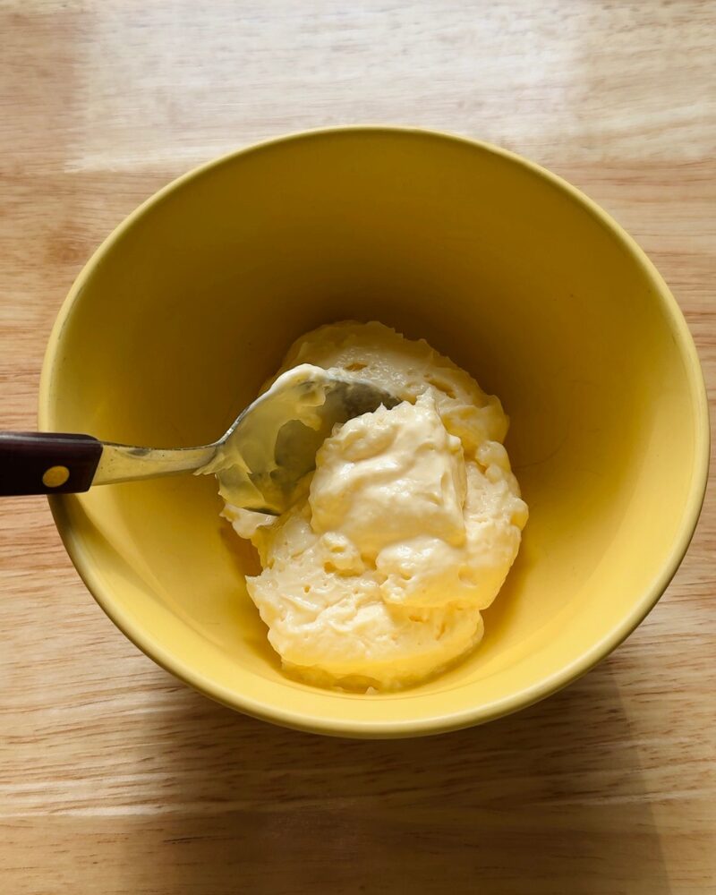 mayonnaise in a yellow bowl with a spoon, used as the base for calabrian chili mayo