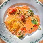 lobster ravioli with creamy tomato basil sauce on white plate
