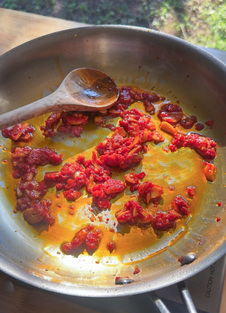 tomato paste cooking in skillet for creamy lobster ravioli sauce